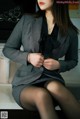 A woman in a gray suit sitting on a kitchen counter.