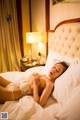 A woman laying on a bed in a white lingerie.