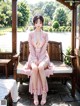 A woman in a pink kimono sitting on a wooden bench.