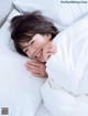 A woman laying in bed with white sheets and pillows.