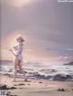 A woman in a white dress standing on a beach.