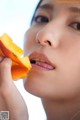 A woman eating a piece of fruit in her mouth.