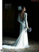 A woman in a white wedding dress holding a bouquet of flowers.